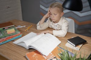 un ragazzo seduto con libri e blocco degli appunti, che respira profondamente con occhi chiusi